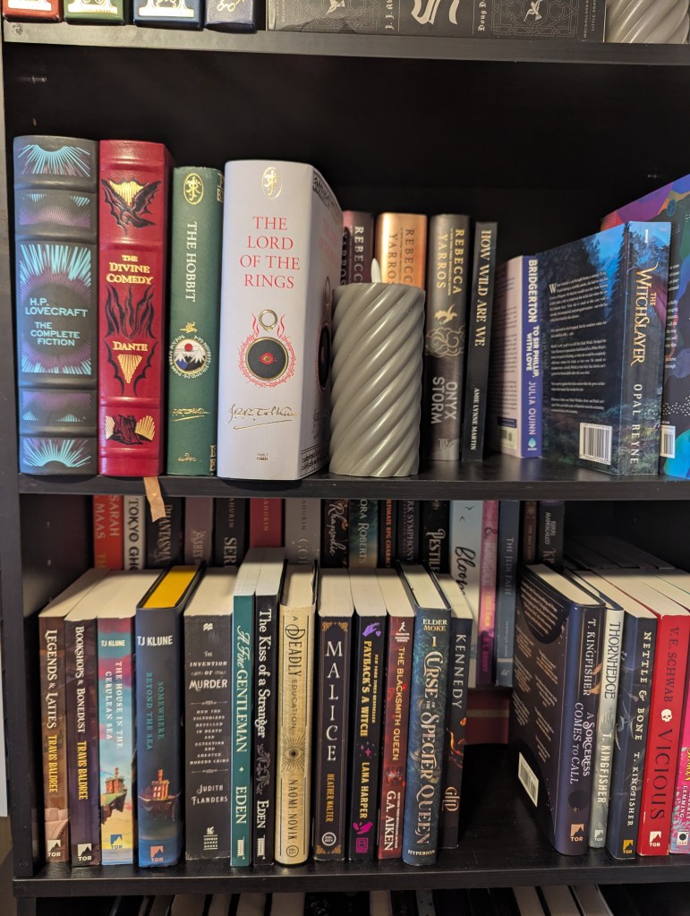 Image of a portion of my bookshelf showcasing a handful of books and a candle.